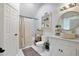 Bright bathroom with a shower, a white vanity, a round mirror, and white walls at 1620 20Th St, Orange City, FL 32763