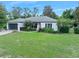Charming home with green lawn, complemented by mature landscaping and an American flag at 1734 Magnolia Ave, Deland, FL 32724