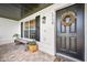 Charming front porch featuring stylish brick flooring, a dark front door, and a wooden bench at 1734 Magnolia Ave, Deland, FL 32724