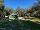 Exterior view of a green steel outbuilding on a wooded property with mature trees and green grass at 17531 Ne 139Th Ave, Fort Mc Coy, FL 32134