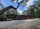 The home's exterior features a metal carport, red accent wall, concrete patio, and gravel driveway at 17531 Ne 139Th Ave, Fort Mc Coy, FL 32134