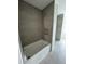 Bathroom with a bathtub surrounded by neutral-toned tile and a glass-enclosed shower at 1856 9Th Ave, Deland, FL 32724