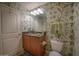 Bathroom with granite counters, wooden cabinets, and green leafy wall paper at 2515 S Atlantic Ave # 203, Daytona Beach, FL 32118