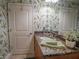 Bathroom featuring wood cabinets, granite counters, and leafy wall paper at 2515 S Atlantic Ave # 203, Daytona Beach, FL 32118