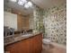 Bathroom with granite counters, wooden cabinets, and green leafy wall paper at 2515 S Atlantic Ave # 203, Daytona Beach, FL 32118