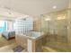 A large bathroom featuring a tub, shower, and glass block wall, with an opening to the bedroom at 2801 Hill St # 801, New Smyrna Beach, FL 32169