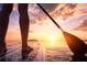 Person standing on a paddleboard enjoying a sunset paddle, encapsulating a lifestyle of outdoor adventure and seaside serenity at 2801 Hill St # 801, New Smyrna Beach, FL 32169