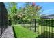 Landscaped backyard featuring a synthetic grass yard, rock border and a black metal fence at 2825 S Asciano Ct, New Smyrna Beach, FL 32168