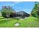A well-maintained backyard featuring a screened-in pool, lush lawn, landscaping, and a secure black metal fence at 2825 S Asciano Ct, New Smyrna Beach, FL 32168