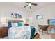 Bright bedroom features a ceiling fan, neutral walls, a wicker headboard and coastal themed artwork and accessories at 2825 S Asciano Ct, New Smyrna Beach, FL 32168