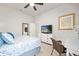 Bright bedroom features a ceiling fan, neutral walls, a TV over a dresser and coastal themed artwork and accessories at 2825 S Asciano Ct, New Smyrna Beach, FL 32168