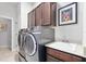 A laundry room with front loading washer and dryer set, dark cabinets, and a utility sink at 2825 S Asciano Ct, New Smyrna Beach, FL 32168