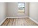 Empty bedroom showcasing wood-look flooring, fresh neutral paint, baseboard trim, and a bright window at 2831 Fifer Dr, Deltona, FL 32738