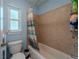 Bathroom featuring a shower-tub combination, large window, and tiled walls at 3013 Hunkin Cir, Deltona, FL 32738