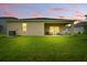 Backyard shot showing a covered patio that extends into the grassy yard at twilight at 317 River Front Way, Edgewater, FL 32141