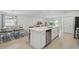 Modern kitchen boasts an extended island with barstool seating, stainless appliances, and seamless flow to dining area at 317 River Front Way, Edgewater, FL 32141