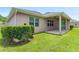 Backyard view with lush grass, partial view of patio with ceiling fan, and exterior wall with windows at 32 Abacus Ave, Ormond Beach, FL 32174