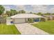 Charming single-story home featuring a metal roof, lovely landscaping, brick paver driveway, and attached garage at 3324 Royal Palm Dr, Edgewater, FL 32141