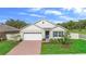 Charming single-Gathering home featuring a brick-paved driveway, well-manicured lawn, and a welcoming blue front door at 33436 Shutterfly Way, Sorrento, FL 32776