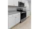 Modern kitchen featuring stainless steel stove/oven and microwave with white cabinets and countertops at 33436 Shutterfly Way, Sorrento, FL 32776