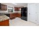 Kitchen with granite counters, wood cabinets, black appliances, tile flooring, and pantry at 3810 Arboreal Ct, Deland, FL 32724