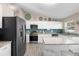 Well-lit kitchen features stainless steel appliances, stylish backsplash, island, and white cabinets at 413 Coventry Estates Blvd, Deltona, FL 32725
