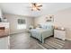Cozy main bedroom with neutral walls, ceiling fan, wood-look tile, and a comfortable sitting area near the window at 413 Coventry Estates Blvd, Deltona, FL 32725