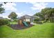 Backyard featuring a wooden swing set with a slide and climbing area and manicured landscaping at 420 Greenridge Ct, Debary, FL 32713