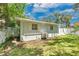 The backyard with light green painted home is surrounded by a wooden fence and several trees at 528 Pine St, Daytona Beach, FL 32114