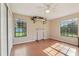 This bedroom features wood floors, a ceiling fan, two windows, and a surfboard mounted on the wall at 5759 Dogwood Rd, Port Orange, FL 32127