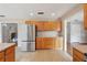 Kitchen with stainless steel refrigerator, wooden cabinets, tile floors, and view into other rooms at 5759 Dogwood Rd, Port Orange, FL 32127