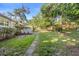 The backyard features a stone path and plenty of green space, shaded by mature trees and a wooden fence at 611 N Garfield Ave, Deland, FL 32724