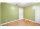 This bedroom features bright green walls, bright windows, laminate floors, and a closet for storage at 611 N Garfield Ave, Deland, FL 32724