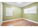 This bedroom features bright green walls, bright windows, and updated laminate floors at 611 N Garfield Ave, Deland, FL 32724