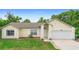 Charming single-story home featuring an attached garage, well-maintained lawn, and light yellow siding at 685 N Firwood Dr, Deltona, FL 32725