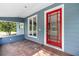 Covered front porch featuring a red front door and red brick flooring adding a pop of color to the home at 710 W May St, Deland, FL 32720