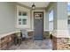Inviting front porch with stone accents, a comfortable chair, and decorative floral arrangements at 7732 Sw 86Th Ct, Ocala, FL 34481
