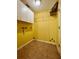 Empty laundry room with yellow walls, brown tile floor, overhead cabinets and a wire shelf at 955 Thelma St, Orange City, FL 32763
