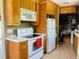 Traditional kitchen features wood cabinets, white appliances, and neutral countertops with an eat-in kitchen area at 1025 Persian St, Deltona, FL 32725
