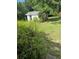 View of the exterior of the backyard shed from behind some landscaping at 110 Amigos Rd, Debary, FL 32713