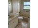 Bathroom features a single sink vanity, a window, and a standard tub with a shower at 1118 Prescott Blvd, Deltona, FL 32738