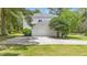 Two-story white home featuring an attached two-car garage and a concrete driveway, surrounded by lush green trees at 1155 Taylor E Rd, Deland, FL 32724