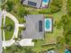 Stunning aerial view of home with screened pool, lush landscaping, solar panels, and circular driveway at 15 Cambridge Trce, Ormond Beach, FL 32174