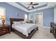 Cozy main bedroom with a tray ceiling, plush bedding, and a doorway to the ensuite bathroom at 1653 Victoria Gardens Dr, Deland, FL 32724