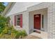 Close-up of the front door and a window with red shutters on a gray brick house at 1730 Birmingham Ave, Daytona Beach, FL 32117