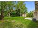 Large green backyard with a basketball hoop, storage shed, mature trees and partial shade at 182 Grove St, Ormond Beach, FL 32174