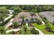 A bird's eye view of this beautiful property, landscaped yard, circular drive, and tile roof, surrounded by lush greenery at 19 Tomoka Cove Way, Ormond Beach, FL 32174