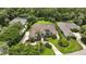 Aerial view of a large home with a clay tile roof, screened-in pool, lush landscaping, and circular drive at 19 Tomoka Cove Way, Ormond Beach, FL 32174