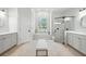 A neutral-toned bathroom boasting a walk-in shower, stand-alone tub under an arched window, and dual sinks at 19 Tomoka Cove Way, Ormond Beach, FL 32174