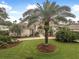 Elegant home with a well-manicured lawn, lush landscaping, and a stately palm tree in the front yard at 19 Tomoka Cove Way, Ormond Beach, FL 32174